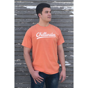 Man wearing a orange short sleeve tshirt with the chillwater vintage chill design on the front center. The design is in a classic white script.