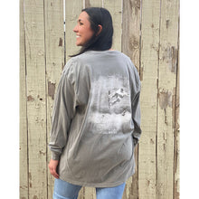 Woman wearing a grey long sleeve shirt with chillwater design on the back. Design features a snowboarder with mountains in the background. 
