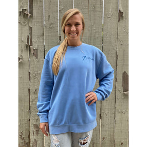 Young woman in blue chillwater sweatshirt with angler design. Front design features a fly fishing hook on the left chest.