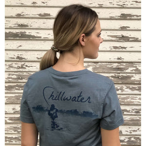 Young woman wearing v-neck chillwater tshirt with angler design. Design features fly fisherman wading in a body of water.