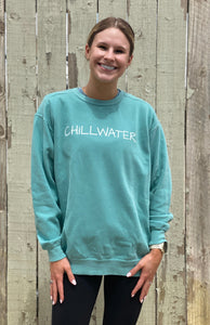 Faded teal comfort color sweatshirt with beach font on front and beach bound design on the back. White sailboat on white sand with an ocean background.