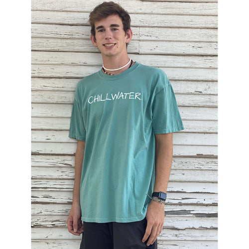 Man in short sleeve teal t-shirt featuring the chillwater logo on the front and beach bound design on the back.