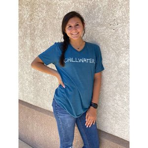 Woman in short sleeve v-neck blue t-shirt featuring the chillwater logo on the front and beach bound design on the back.