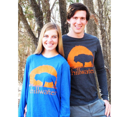 Young male and female wearing a dark grey and electric blue Buffalo long sleeve by Chillwater with trees in the background. 