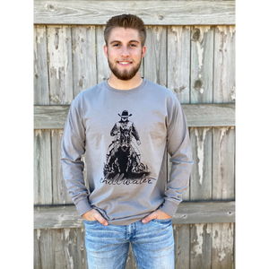 Young male wearing a concho steal grey long sleeve tee in the Rawhide design by Chillwater. The front pictures a cowboy on horseback.