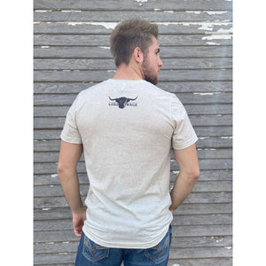 Young male wearing a cream of wheat short sleeve tee with the Highlander design by Chillwater. The front resembles a western portrait of a Highlander cow.