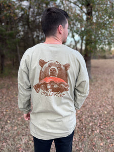 Young male wearing a cobblestone khaki long sleeve tee in the Grizzly design by Chillwater. The back pictures a grizzly bear with a bright pink salmon in its mouth.