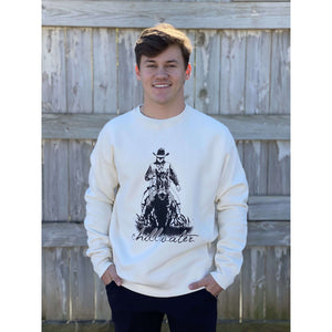 Young male wearing a cream of wheat sweatshirt in the Rawhide design by Chillwater. The front pictures a cowboy on horseback.