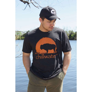 Young male standing at the water font with a short sleeve shirt from Chillwater Buffalo design, in dark grey and orange logo.