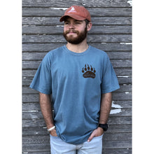 Young male wearing a cornflower blue short sleeve tee in the Grizzly design by Chillwater. The back pictures a grizzly bear with a bright pink salmon in its mouth.