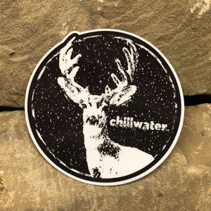 A circle sticker in black and white of Chillwater's Snowy Buck Design, where there is a deer surrounded by snowfall