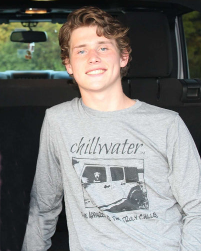 Young male wearing a barn metal grey long sleeve tee in the Jim Tom design by Chillwater. The front pictures a dog sitting in a jeep.