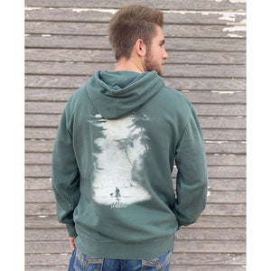 Young male wearing a trees of evergreen sweatshirt hoodie with the Kayak design by Chillwater. The back resembles a kayaker floating down a river covered by trees.