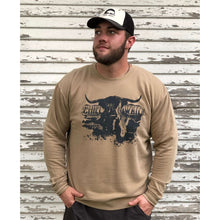 Young male wearing a cobblestone khaki sweatshirt with the Highlander design by Chillwater. The front resembles a western portrait of a Highlander cow.