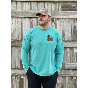 Young male wearing a tropical timid teal long sleeve tee in the Grizzly design by Chillwater. The back pictures a grizzly bear with a bright pink salmon in its mouth.