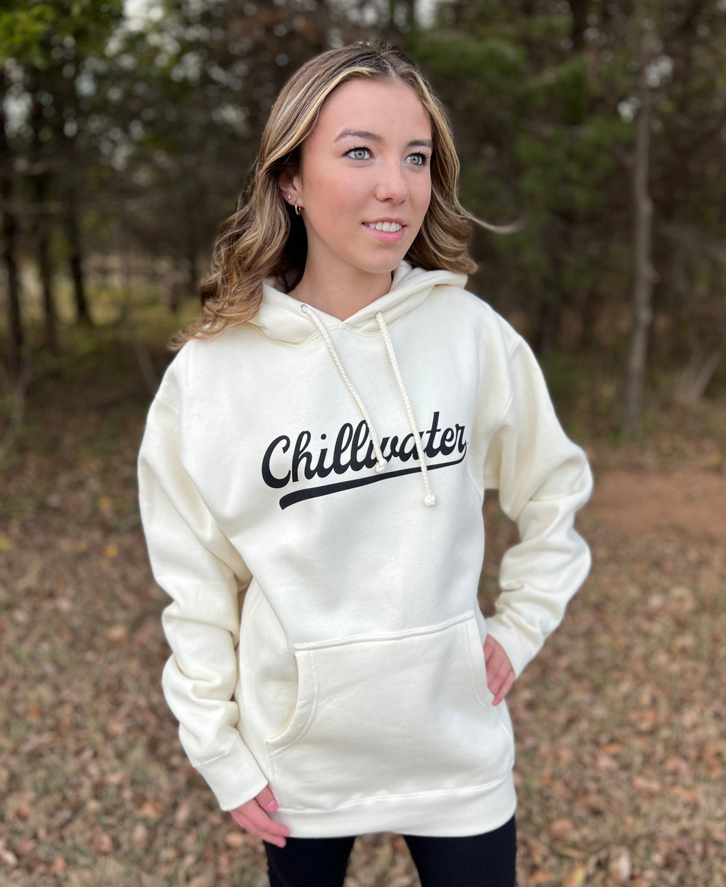 Young female wearing a washed cream hoodie in the Vintage Chill design by Chillwater. The front shows the words “chillwater” in beautiful flowing font.
