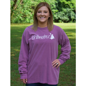 Young female wearing a dark leaf magenta long sleeve tee with the Kayak design by Chillwater. The back resembles a kayaker floating down a river covered by trees.