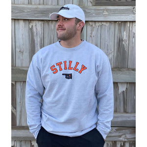 Grey heavy sweatshirt with chillwater's stilly logo in orange and black lettering. Also in the logo is a small black oklahoma icon with an orange star over the stillwater location.