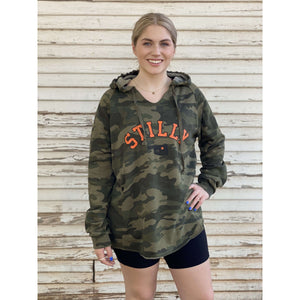 Green camo v-neck hoodie sweatshirt with chillwater's stilly logo in orange and black lettering in chest center. Included in the logo is a small black oklahoma icon with an orange star over stillwater location.