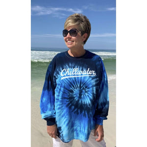 Woman wearing tye dye blue and navy chillwater vintage chill long sleeve. Design is in a white script font on the front center.