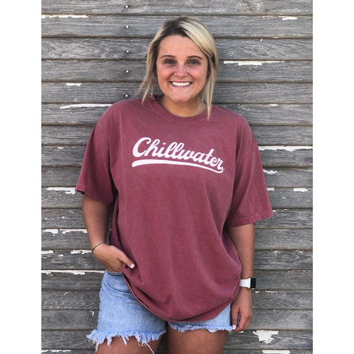 Girl wearing a red short sleeve tshirt with the chillwater vintage chill design on the front center. The design is in a classic white script.
